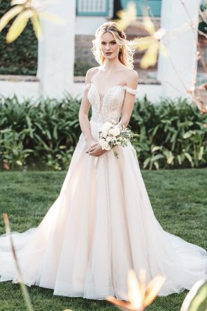 A sequined, beaded off-shoulder bodice in a botanical motif is the perfect pairing for this sparkling A-line tulle gown.