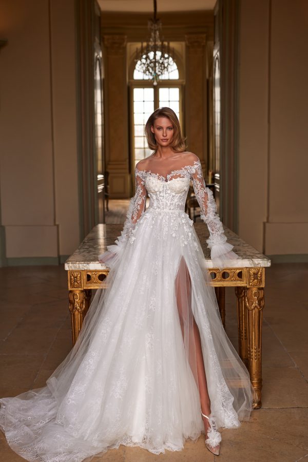 Sinatra by Milla. A Magnificent A-line semi-transparent wedding gown crafted from chantilly lace, delicately sprinkled with 3D flowers and sequins. Boasting a heart-shaped semi-transparent corset with built-in cups, adorned with 3D floral appliqués and sequins, a zip closure on the back, and a voluminous tulle