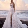 Opal by Milla Nova. A Romantic A-line wedding gown crafted from delicate lace with intricate floral detailing and sparkling all-over sequins. Featuring a boned drop-waist semi-sheer lace corset that flatters the figure, a heart-shaped neckline with subtle V-cut and detachable cups, embellished spaghetti straps, and a closed back with a zip closure. The maxi skirt, made from layers of lace with a nude underskirt, flows gracefully into a midi train, adding an ethereal finish. 
The gown can be elevated with an Opal fingerless gloves.