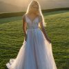Radiant and graceful, this A-line gown features pearl, beaded, and embroidered lace appliques that glisten over layers of sparkle tulle. The V-neckline and slender straps create a flattering, open frame, while the natural waist flows into a soft, sweeping skirt. With its gentle shimmer and intricate lacework, this gown captures a beautifully romantic sensibility with just the right touch of light-catching detail.